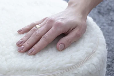 Kobieca dłoń oparta o białą poduszkę do jogi.