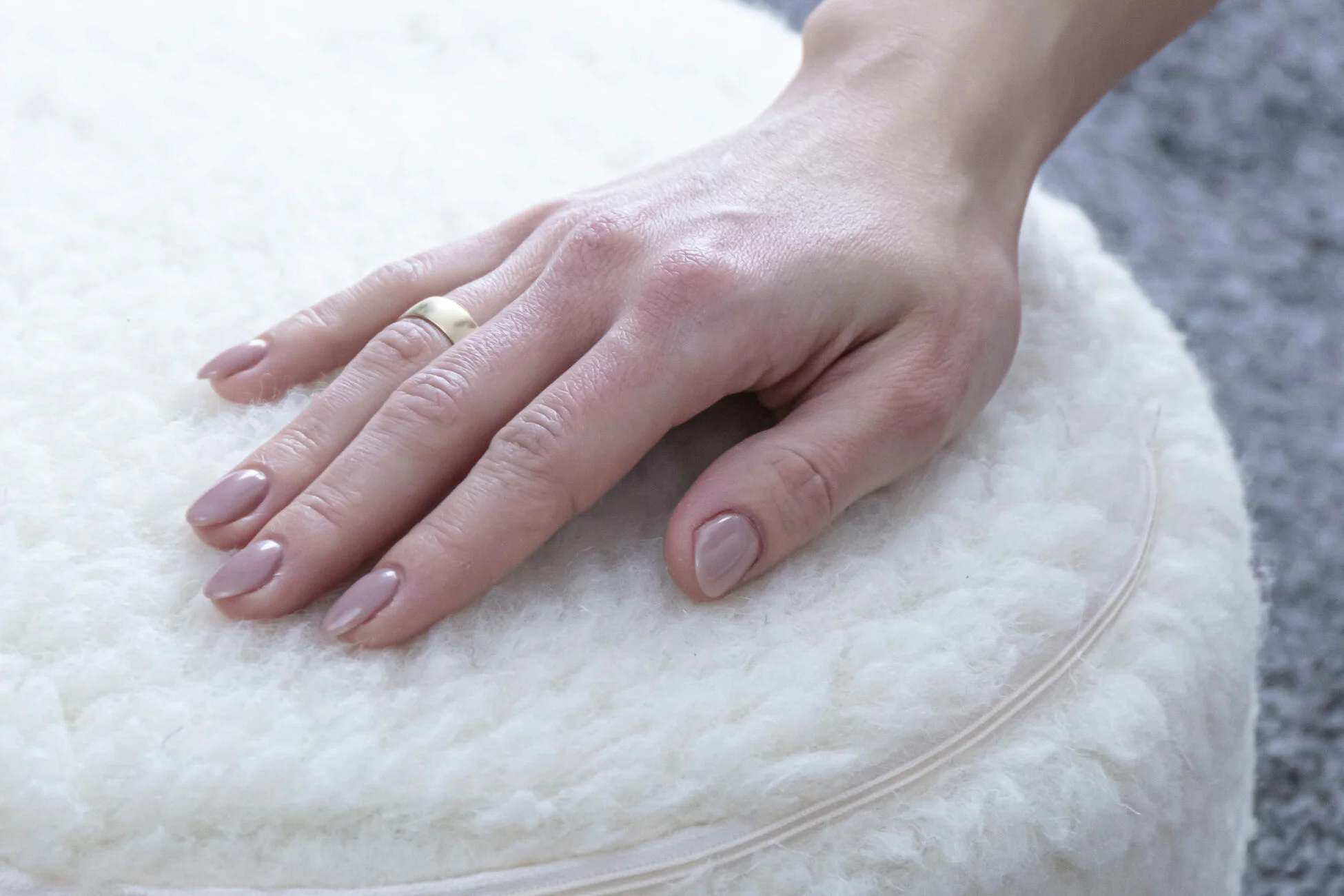 Kobieca dłoń oparta o białą poduszkę do jogi.