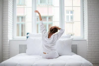 Kobieta przeciągąjąca się na łóżku. W tle poduszki medico silver