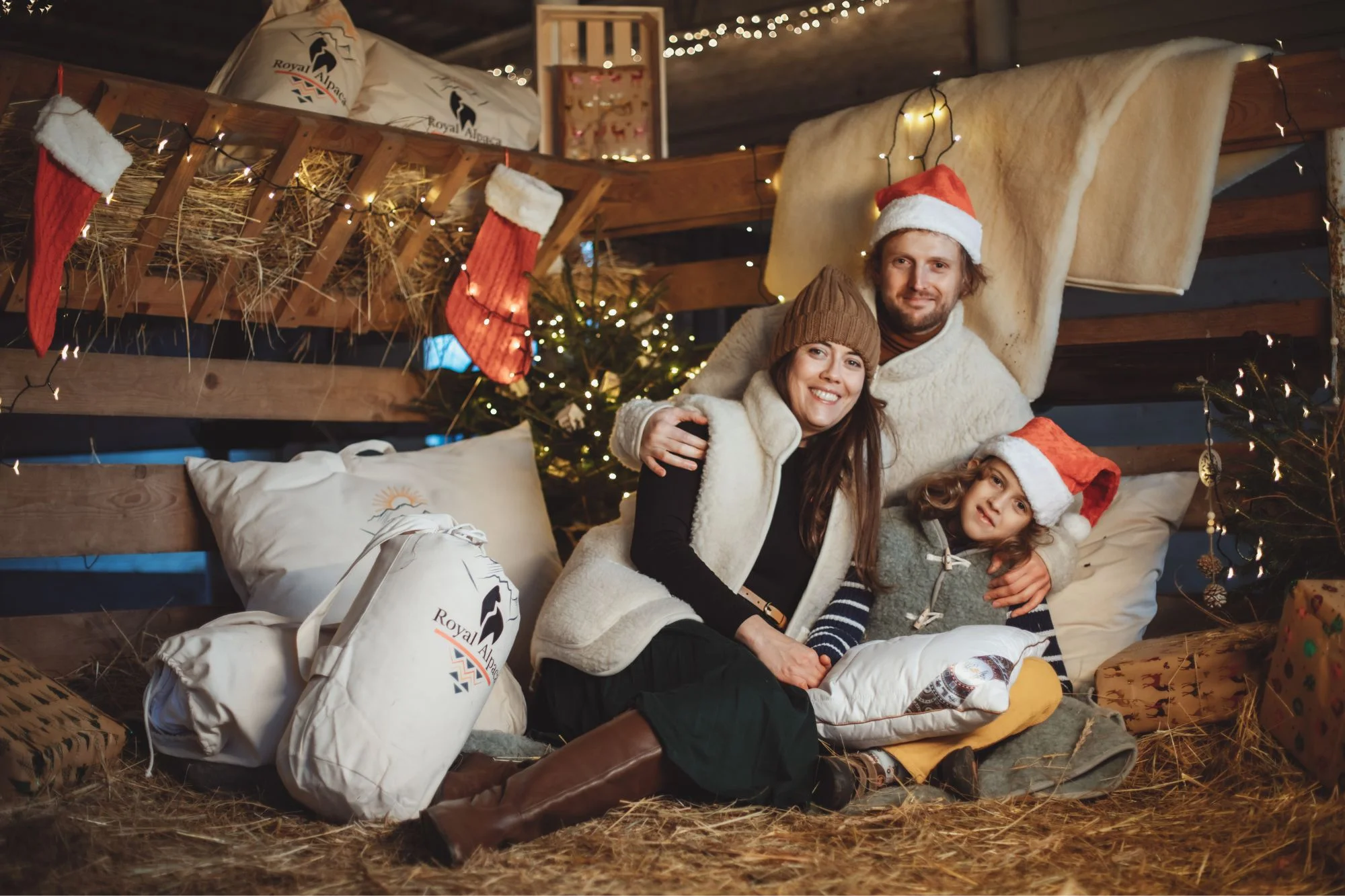 Rodzina w stajni z poduszką i kocem w świątecznej aranżacji