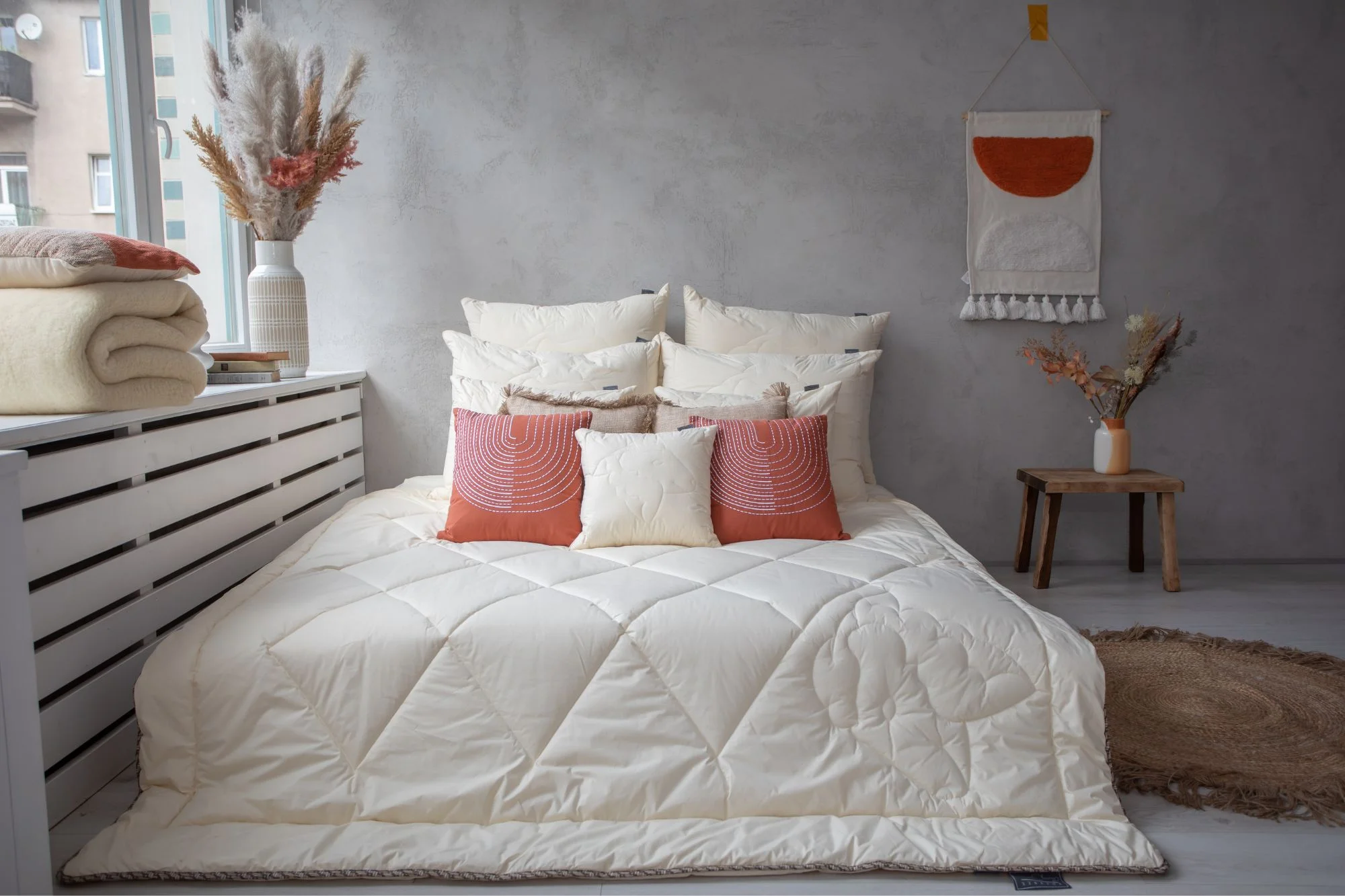 Łóżko na nim kołdra i poduszki welniane