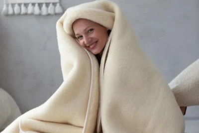 Kobieta zawinięta w beżowy koc wełniany