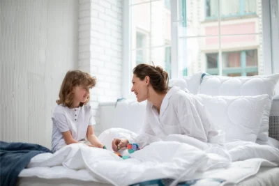 Chłopiec i mama bawią się klockami na łóżku. W tle poduszki antyalergiczne medico silver.