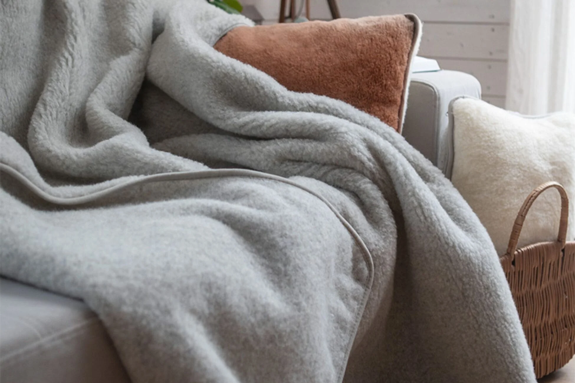 Kanapa, na niej wełniany koc i poduszka z wełny