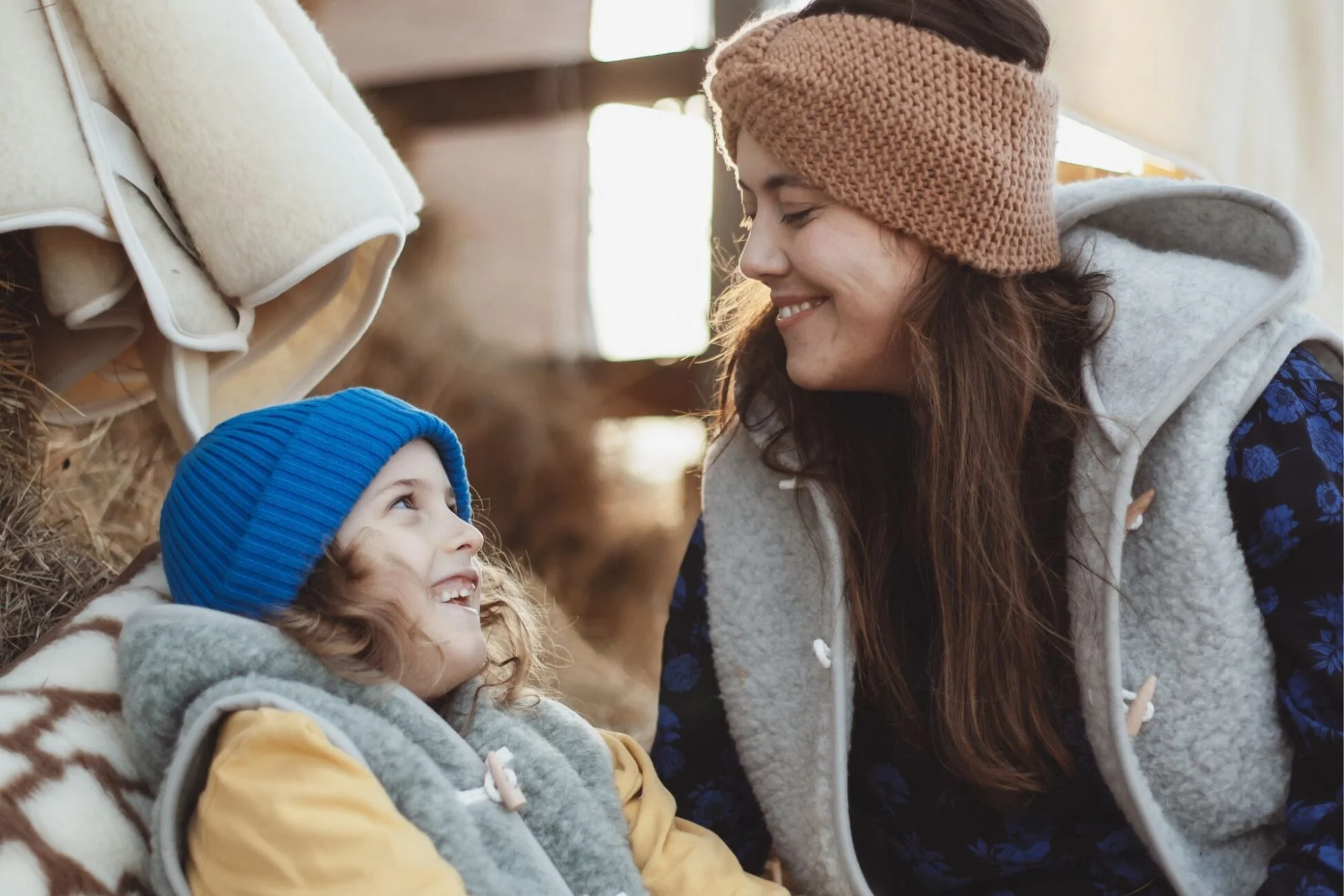 Kobieta z synem, ubrani w kamizelki wełniane, śmieją się.