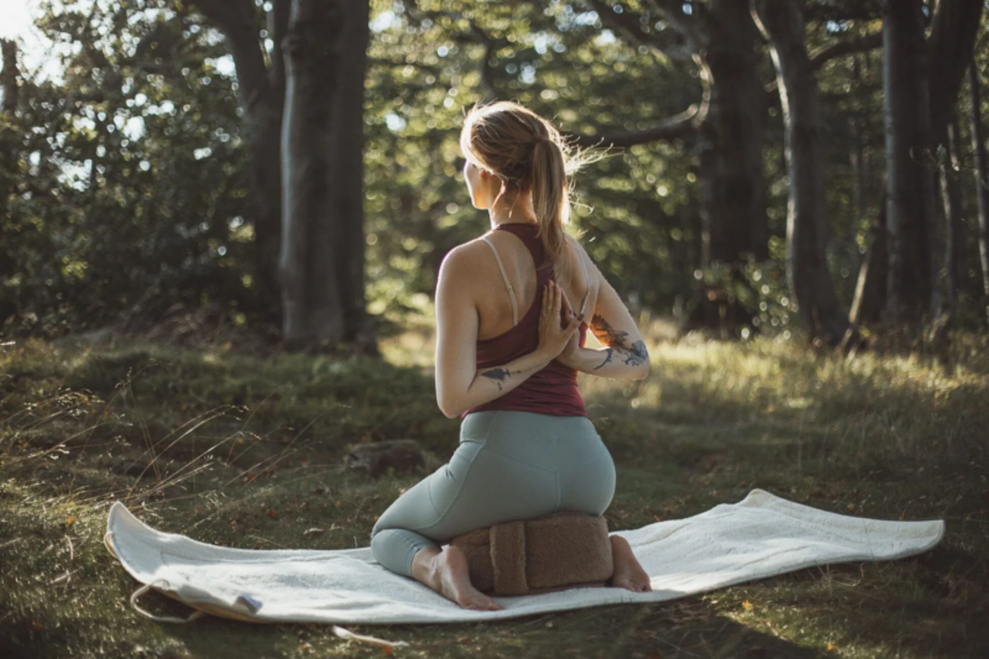 Kobieta praktykująca jogę w plenerze. Używa wełniane akcesoria do jogi.