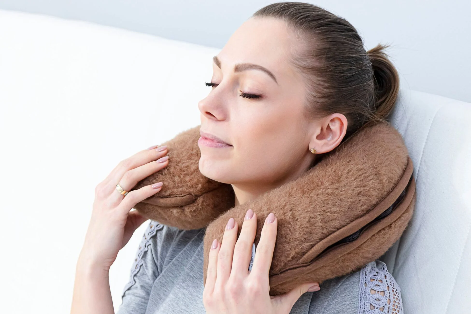 Kobieta relaksuje się z rogalem podróżnym - brązowym na szyi