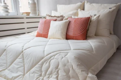 Jasna sypialnia. Łóżko - na nim kołdra merino i poduszki.