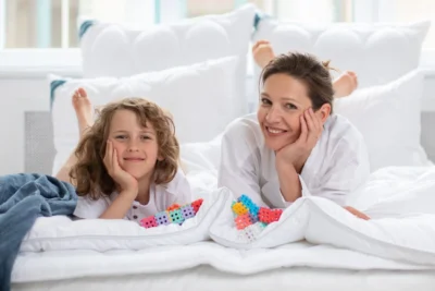 Chłopiec i kobieta leżą na białej kołdrze