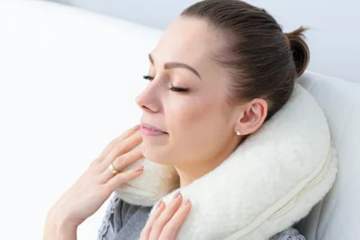 Kobieta relaksująca się z poduszką / rogalem podróżnym na szyi