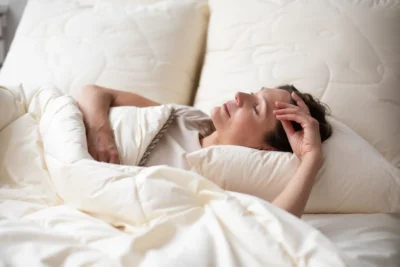 Kobieta śpiąca pod kołdrą naturalną.