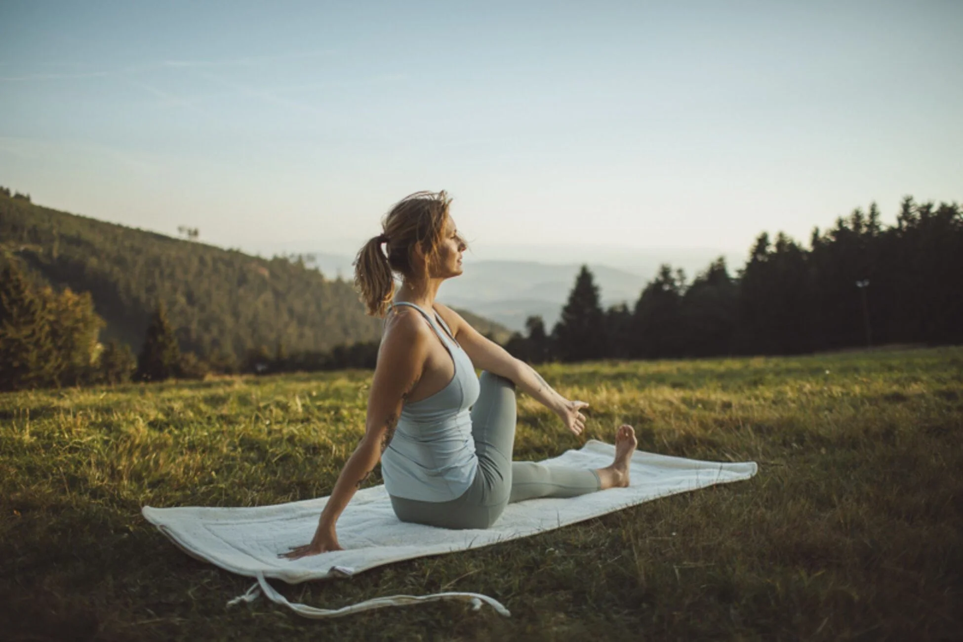 Kobieta ćwicząca jogę w plenerze. Praktykuje na macie wełnianej