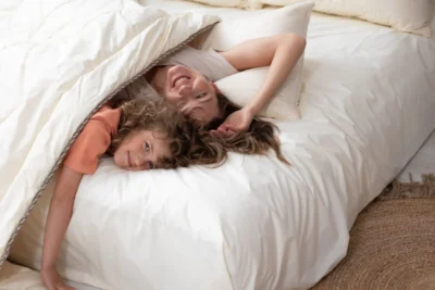 Kobieta i chłopiec, leżą otuleni kołdrą z wełny merino