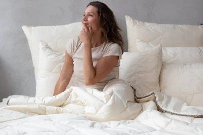 Kobieta siedząca w łóżku pod kołdrą merino line