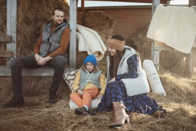 Rodzina w kamizelkach z wełny. siedzi na sianku