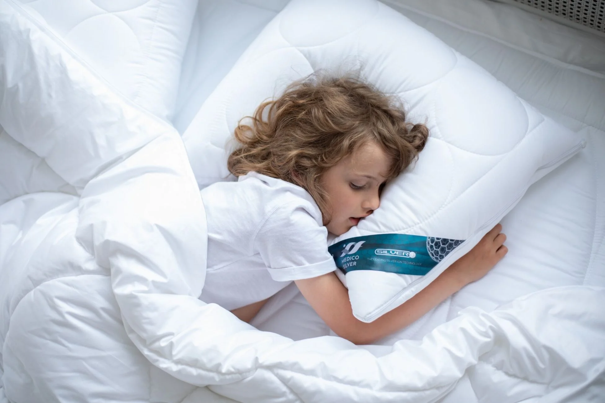 Chłopiec śpiący na poduszce i pod kołdrą z jonami srebra