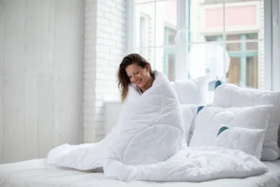 Kobieta owinięta w białą kołdre antyalergiczną