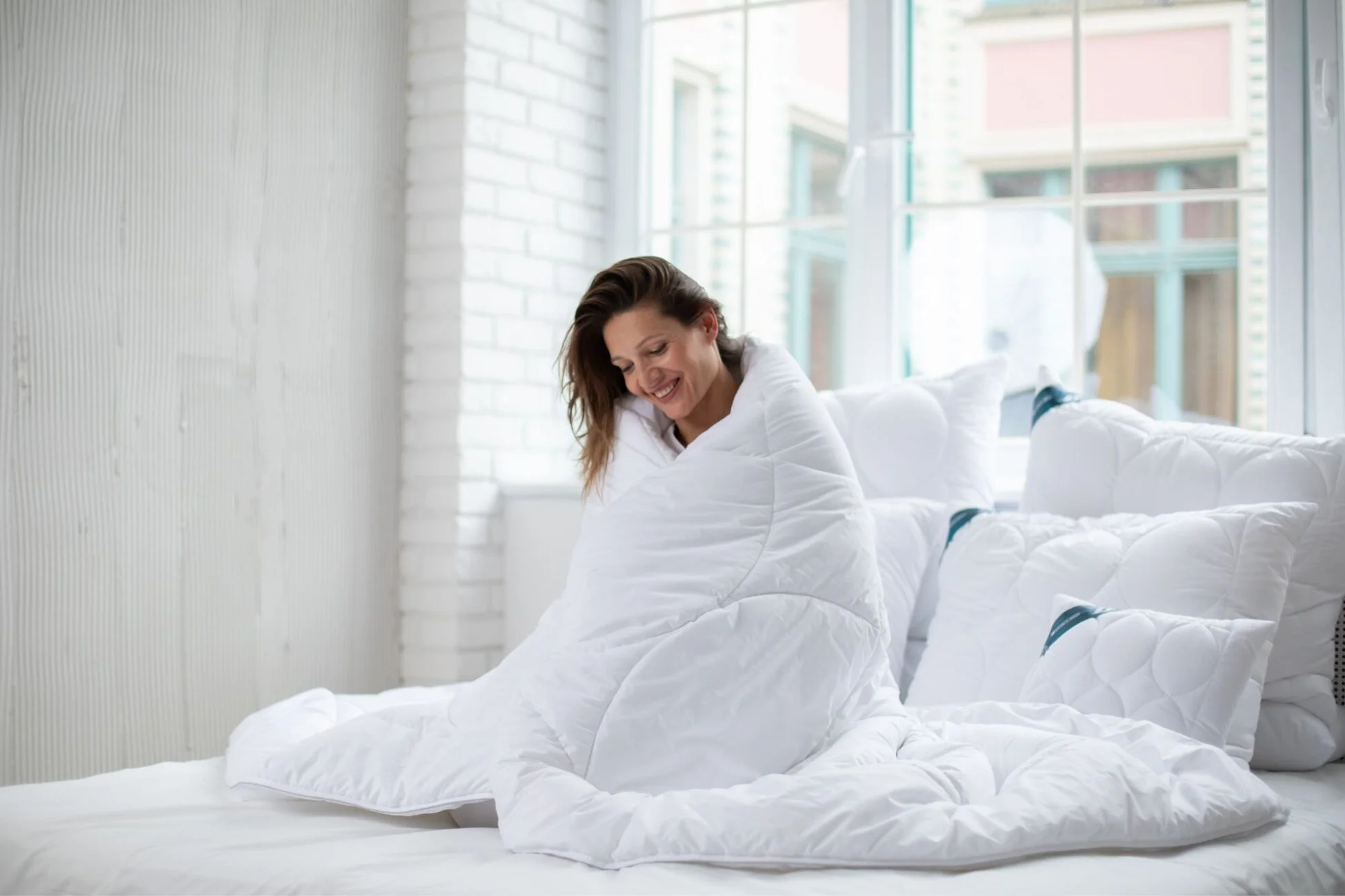 Kobieta owinięta w białą kołdre antyalergiczną