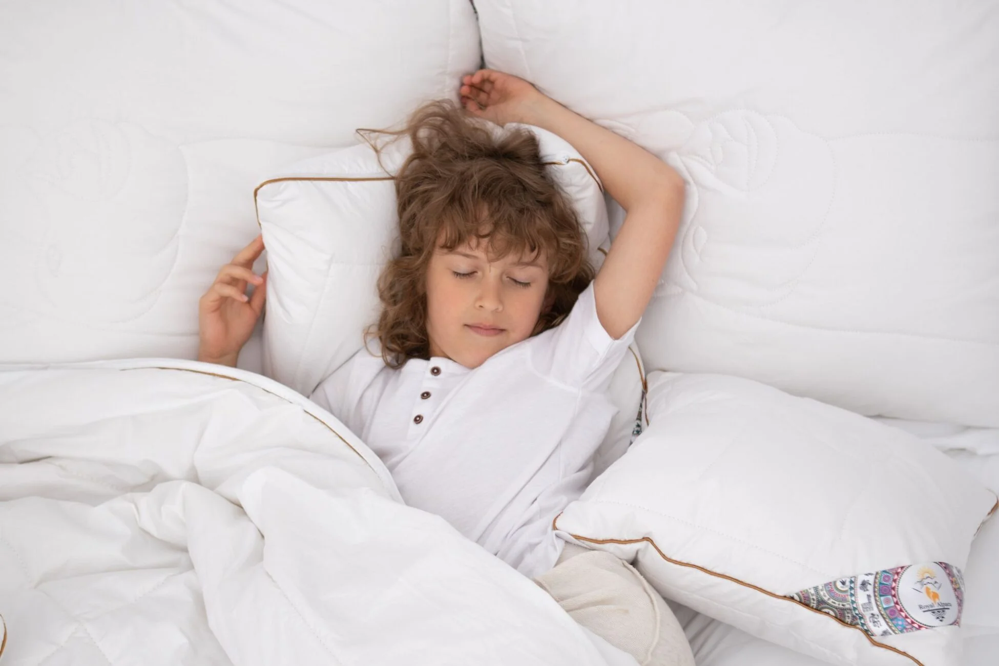Chłopiec śpiący w białej pościeli