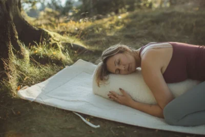 Kobieta praktykująca jogę, leży na bolsterze z wełny.