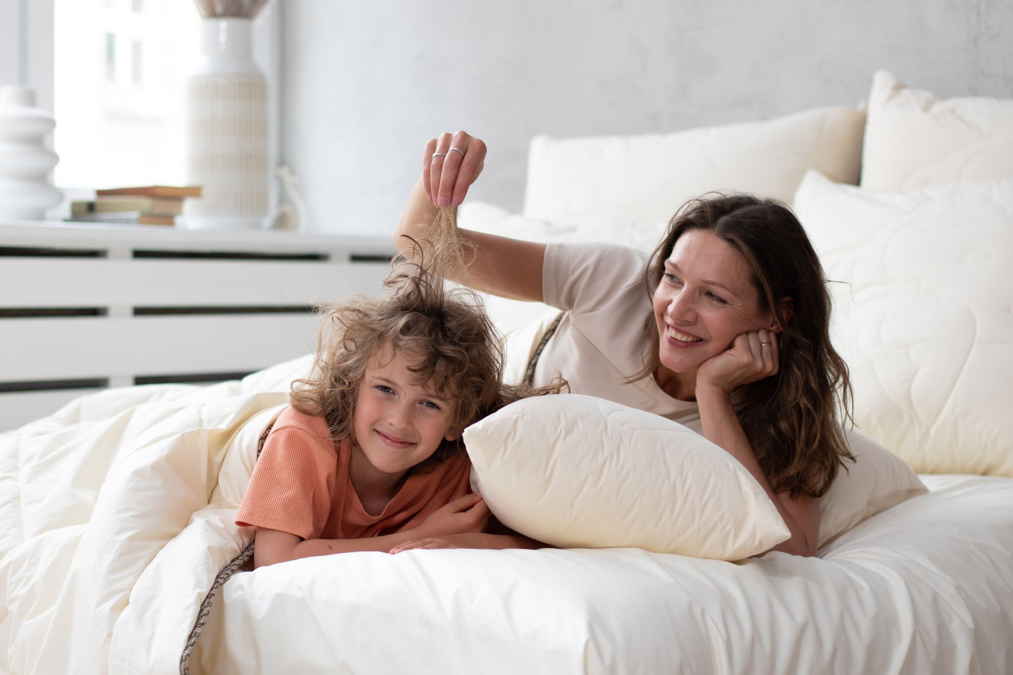 Kobieta i chłopiec leżący w łóżku, śmieją się