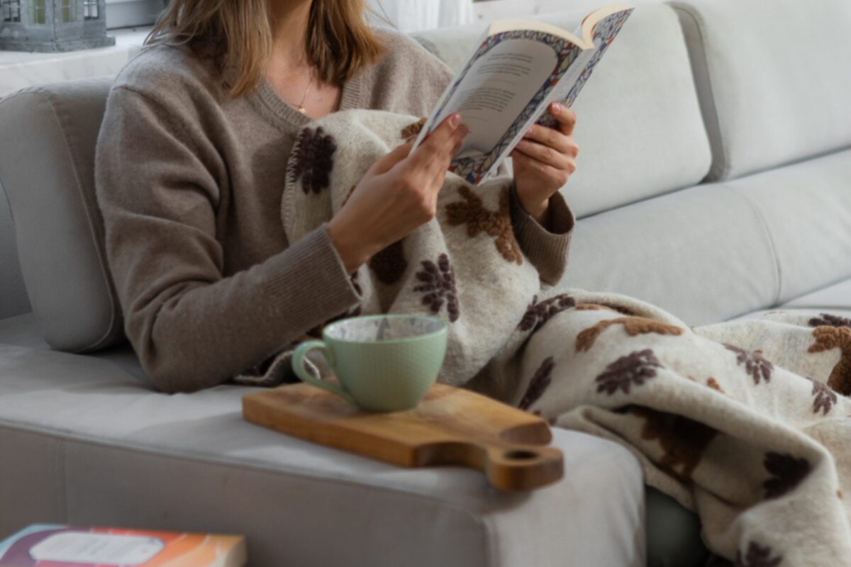 Kobieta owinięta w koc wełniany z wzorem gwiazdek i jeleni.