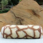 wełniany wałek w kolorze kremowym z brązowym wzorem na tle naturalnego drewna