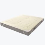 Ochraniacz na materac w kolorze kremowym na materacu.