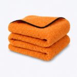 pomarańczowy koc z czarnym wykończeniem na neutralnym tle