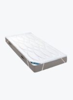 Ochraniacz na materac w białym kolorze na szarym materacu.