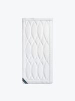 Biały ochraniacz na materac o pikowanym wzorze na jasnym tle