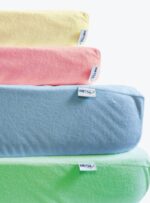 cztery prześcieradła w kolorach żółtym, różowym, niebieskim i zielonym na neutralnym tle