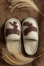 wełniane kapcie w kolorze kremowym z brązowymi jelonkami na tle brązowego materiału