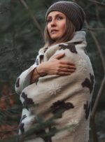 Kobieta owinięta wełnianym kocem w lesie