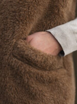 brązowy materiał wełniany z kieszenią i ręką w szarym swetrze