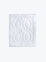 biała kołdra o pikowanym wzorze na neutralnym tle