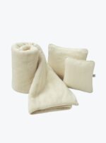 Koc i dwie poduszki wełniane ecru na neutralnym tle