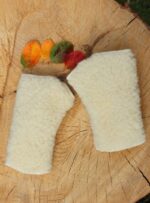 wełniane rękawiczki w kolorze ecru na drewnianym tle z liśćmi