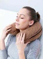 Kobieta w szarej bluzce relaksuje się z brązowym podparciem na szyję