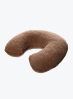 brązowa poduszka w kształcie rogala na neutralnym tle