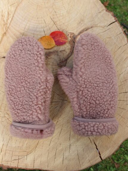 Różowe rękawice na drewnianym plastrze z liśćmi w kolorach jesieni