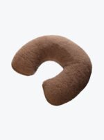 brązowa poduszka w kształcie rogala na neutralnym tle