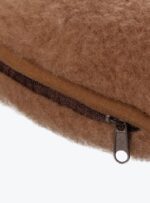 brązowa poduszka rogal z wełny z zamkiem błyskawicznym na neutralnym tle