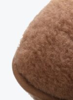 brązowa poduszka rogal z wełny na jasnym tle