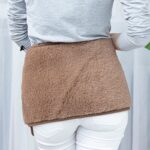 brązowy pas wełniany na plecach osoby w szarej bluzie i białych spodniach w jasnym wnętrzu