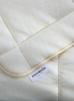 jasna kołdra z wełny z metką na neutralnym tle