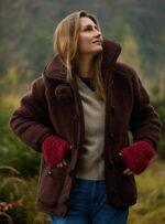 Kobieta w ciemnobrązowej kurtce i czerwonych rękawiczkach w lesie