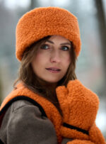 Kobieta w pomarańczowej opascei rękawiczkach i kamizelce w zimowym otoczeniu