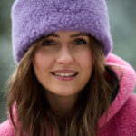 Młoda kobieta w różowej kamizelce i fioletowej opasce wełnianej na tle zimowego krajobrazu