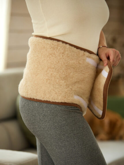 Beżowy pas wełniany na biodrach kobiety w szarych legginsach w domowym wnętrzu